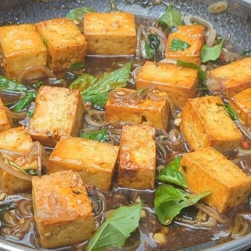 Cubes of Tofu braised in a thai basil sauce in frying pan