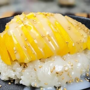 Mango Sticky Rice with Sesame seeds on a black plate