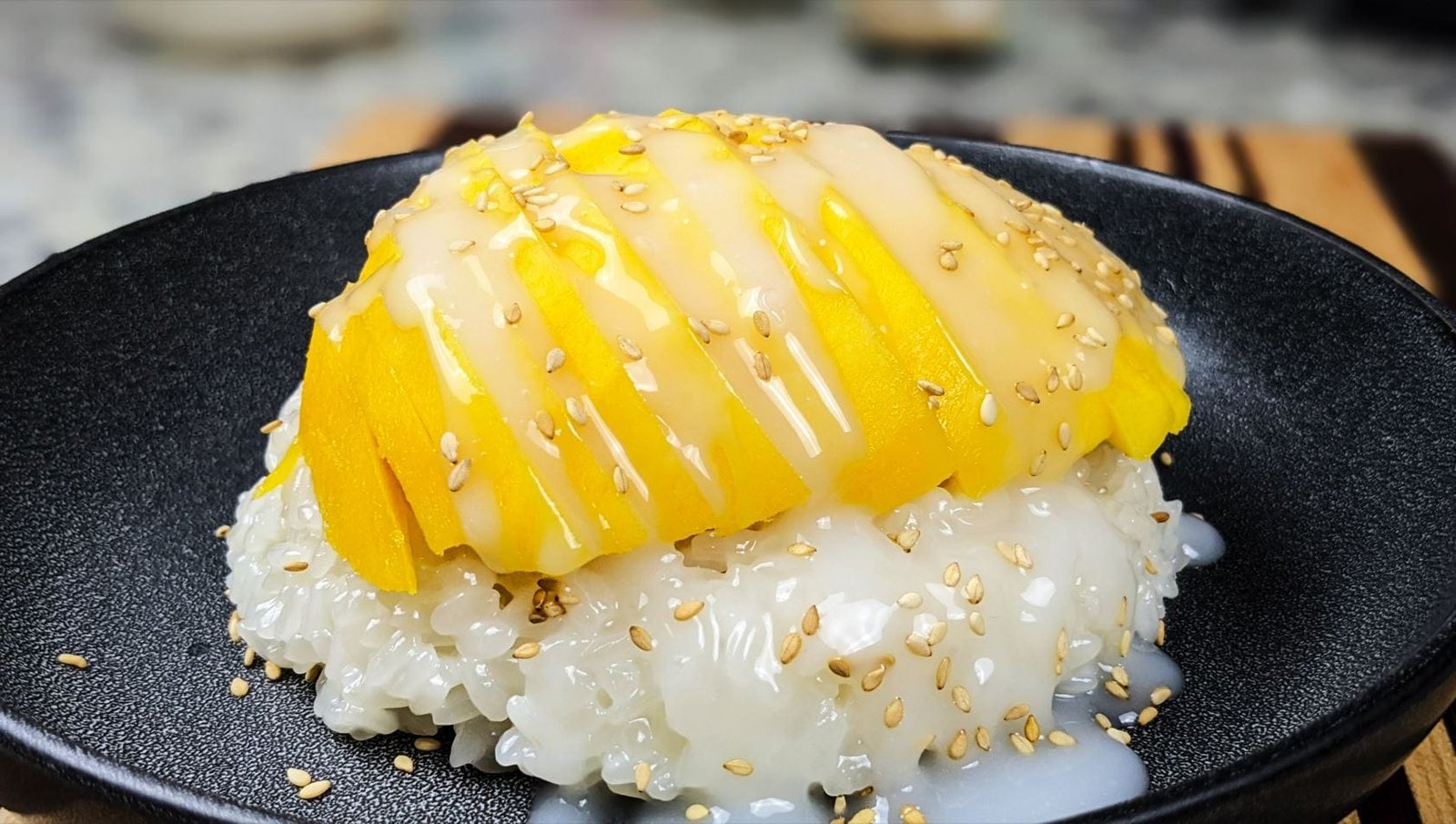 Mango Sticky Rice with Sesame seeds on a black plate