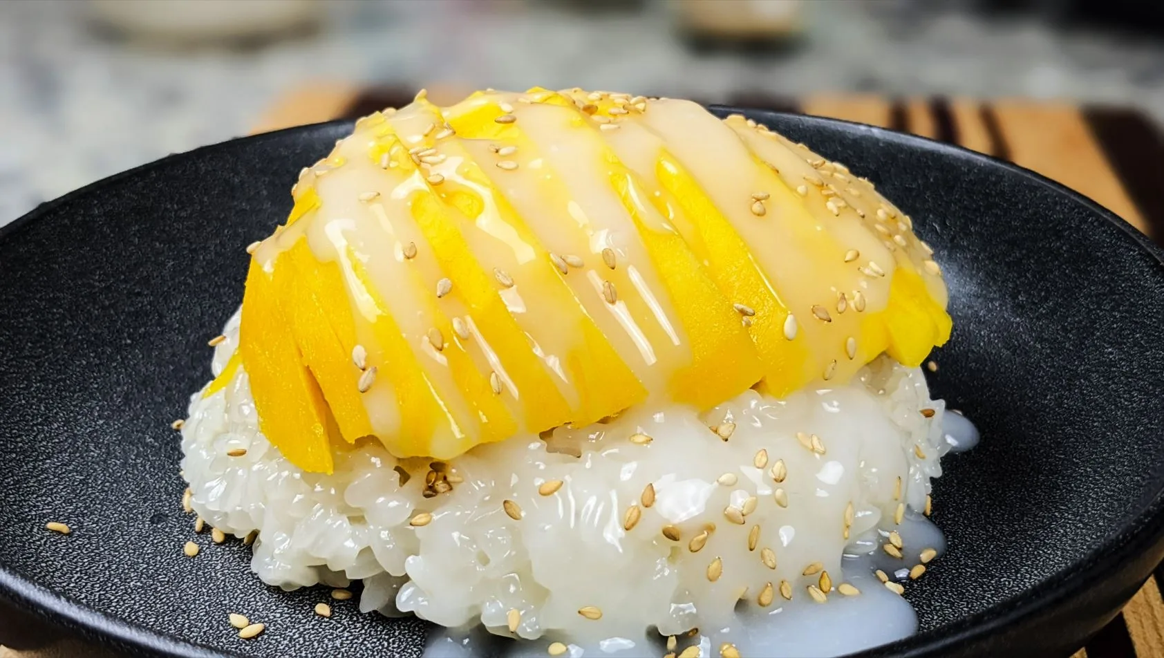 Mango Sticky Rice with Sesame seeds on a black plate