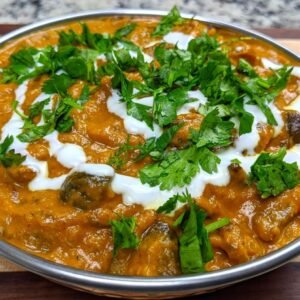 Mushroom Masala served in a traditional kadai with garnish or yogurt and fresh cilantro