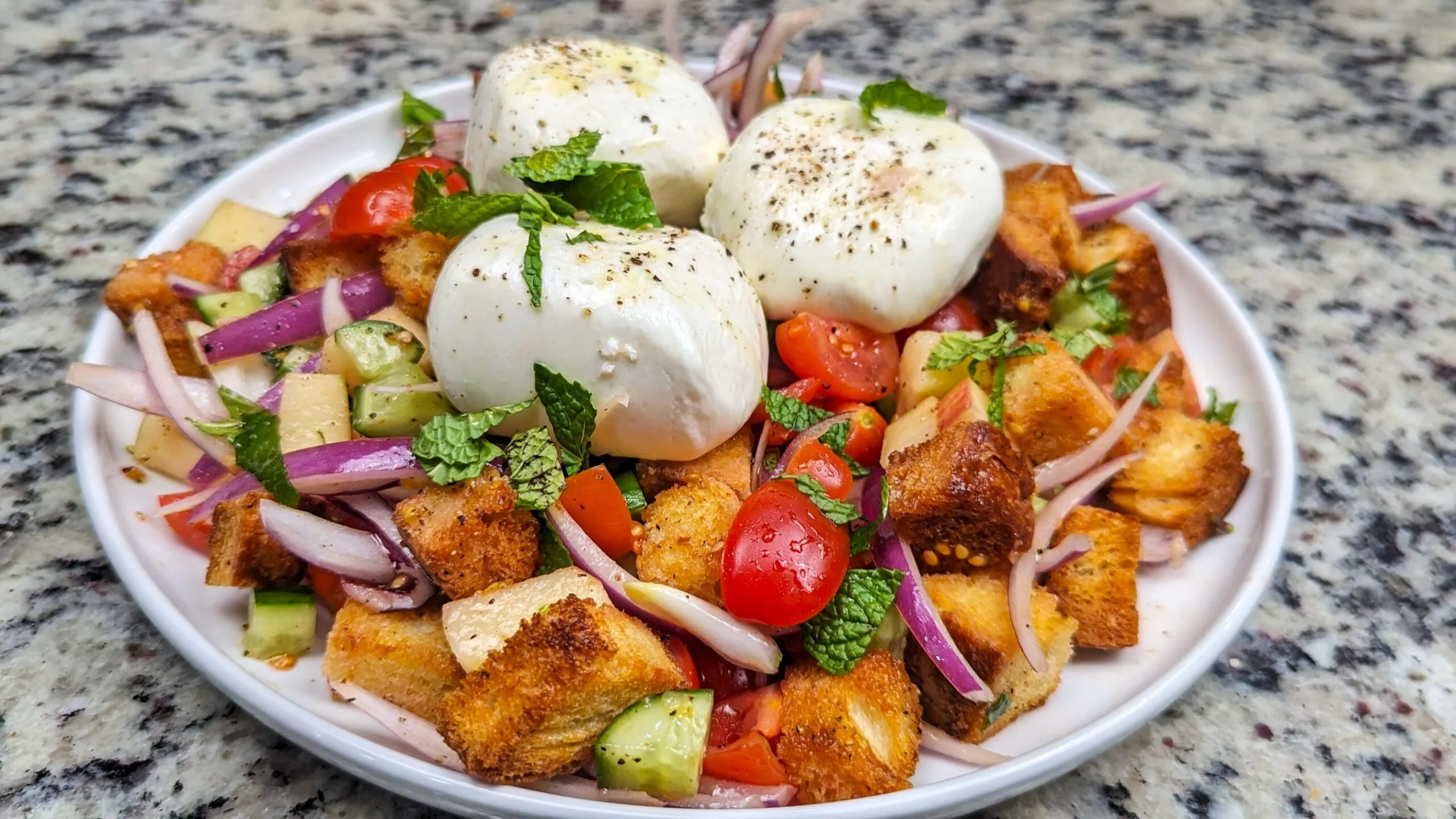Burrata Panzanella salad on a white plate