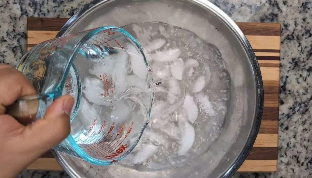 adding water to ice in a bowl for an ice bath