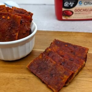 Gochujang Tofu Jerky placed on a wooden plank