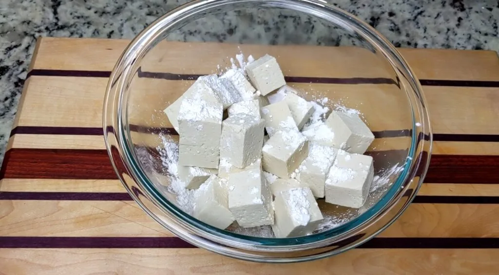 Coating Tofu with Corn Starch in a clear bowl