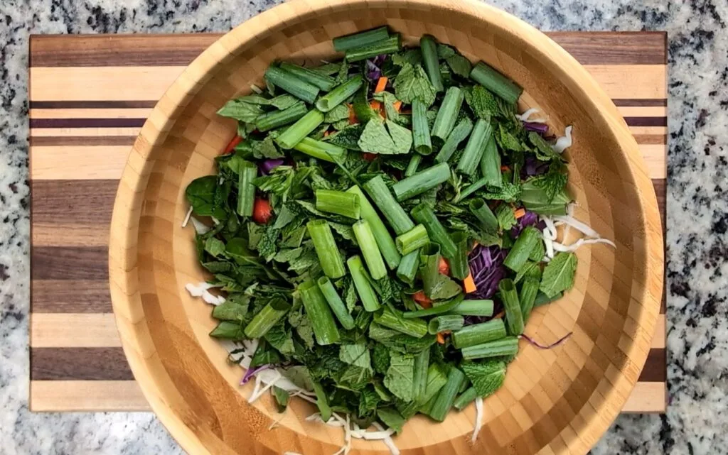 putting all cut vegetables in a brown wooden bowl