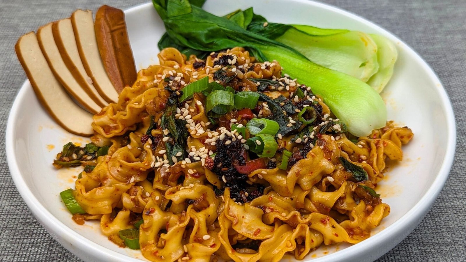 Chili Garlic Noodles served with slices of Tofu and Bok Choy in a white bowl
