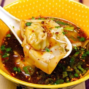 Tofu Wonton on a spoon over a dipping sauce