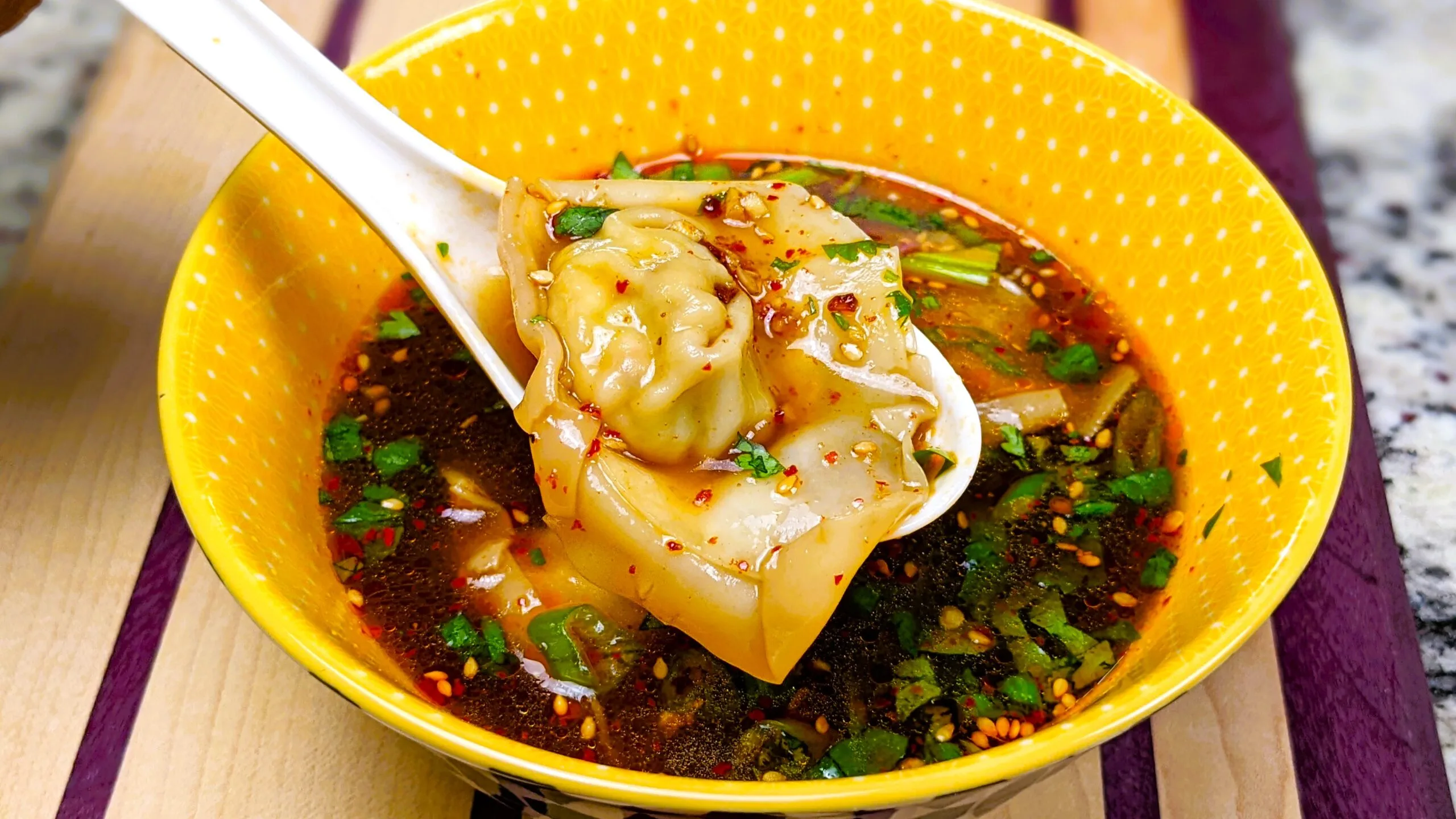 Tofu Wonton on a spoon over a dipping sauce