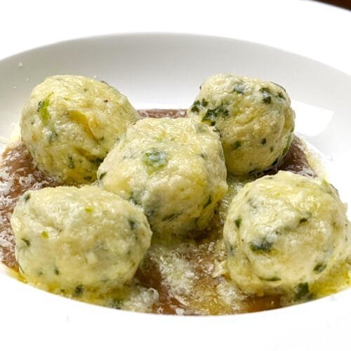 Spinach Ricotta Gnudi on a mushroom puree in a white plate