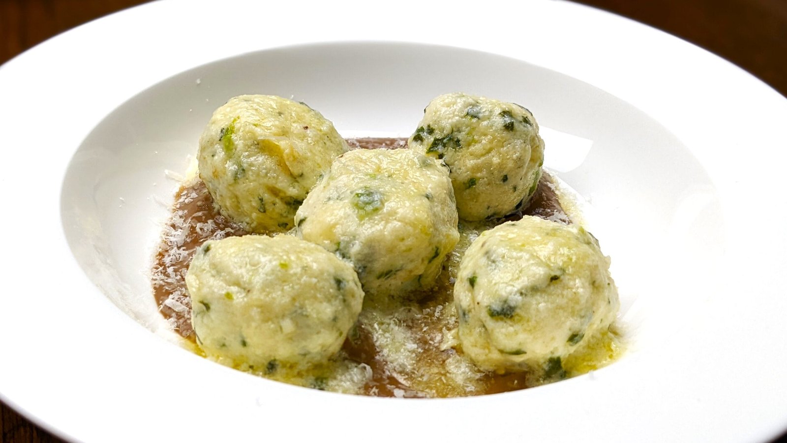 Spinach Ricotta Gnudi on a mushroom puree in a white plate