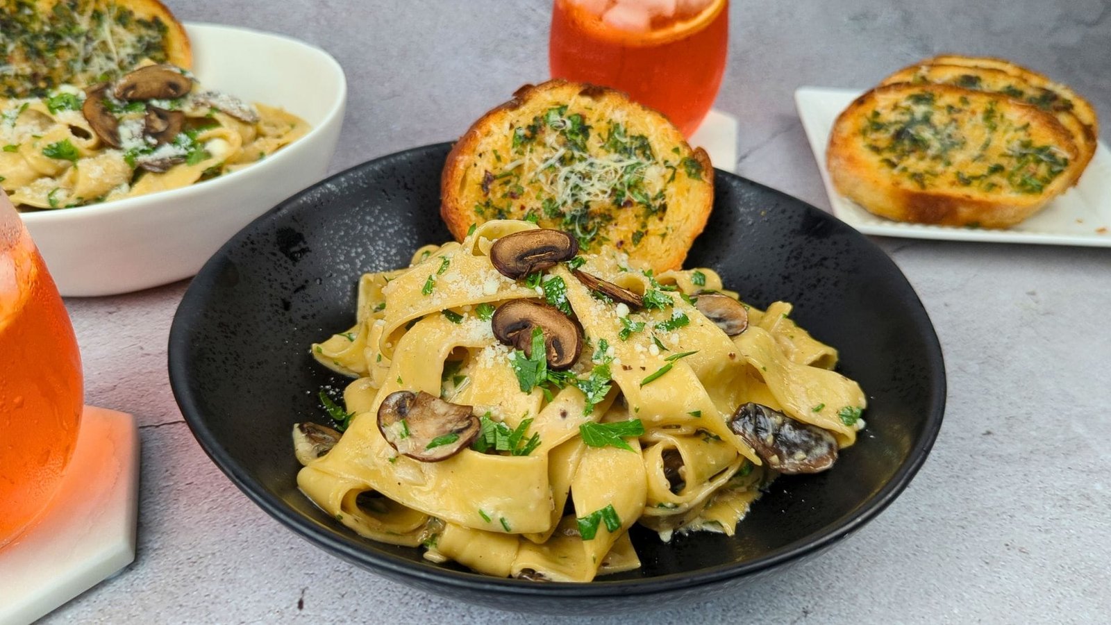 Mushroom Pappardelle Pasta served in a black bowl with garlic bread
