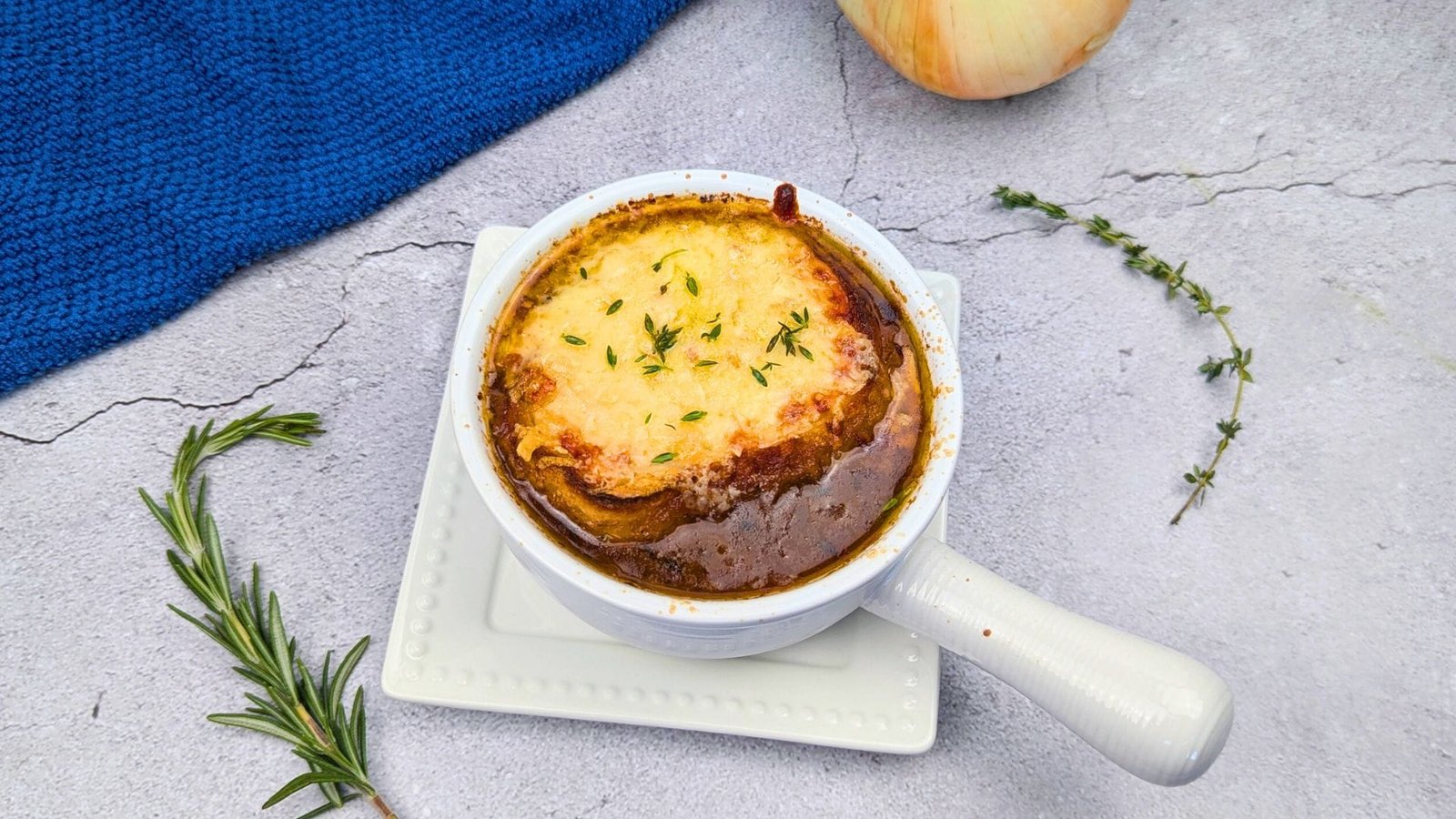 French Onion Soup served in a white bowl with crouton topped with melted cheese
