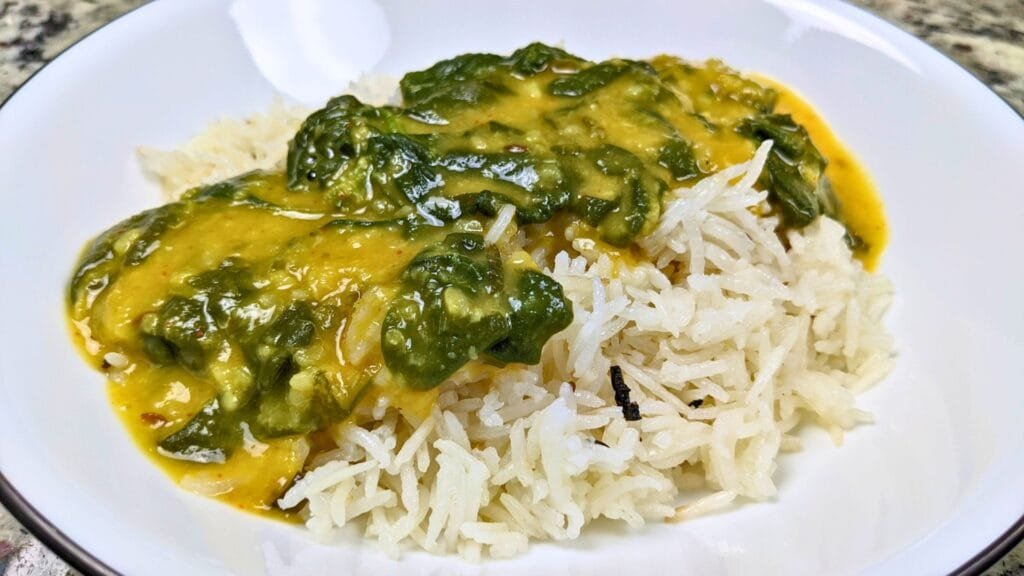 Spinach And Lentil Dal served with Rice on a White plate