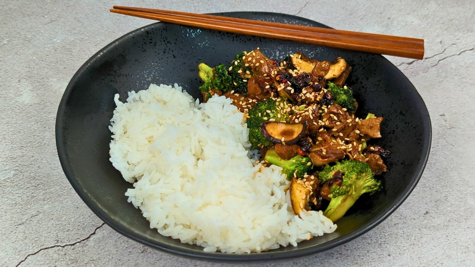 Vegan Beef and Broccoli served with white rice in a black bowl