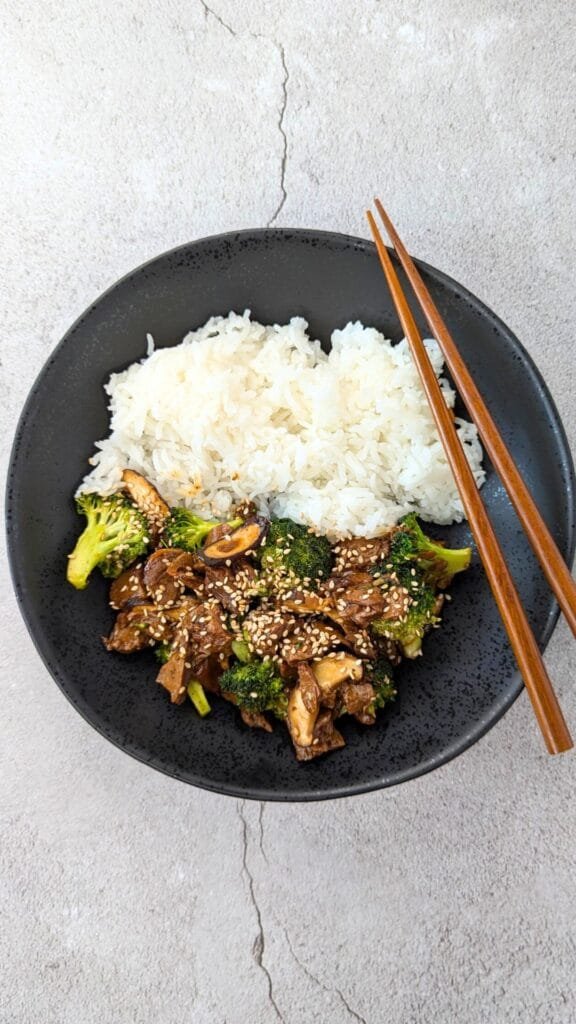 Vegan Beef Broccoli in a black bowl vertical picture