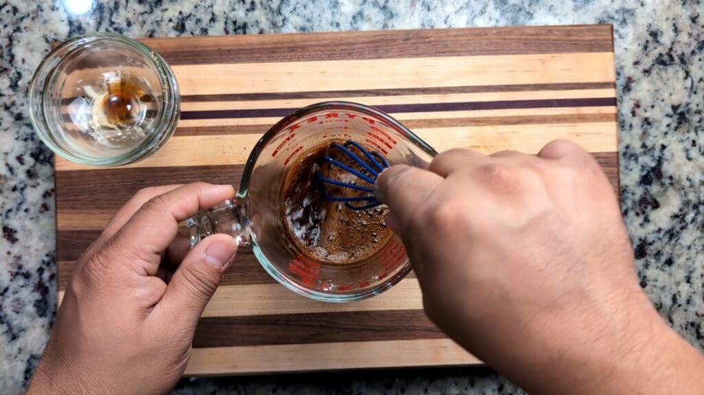 Stirring Stir fry sauce in a clear glass measuring cup