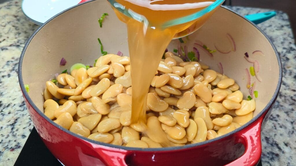 adding vegetable stock to the pot