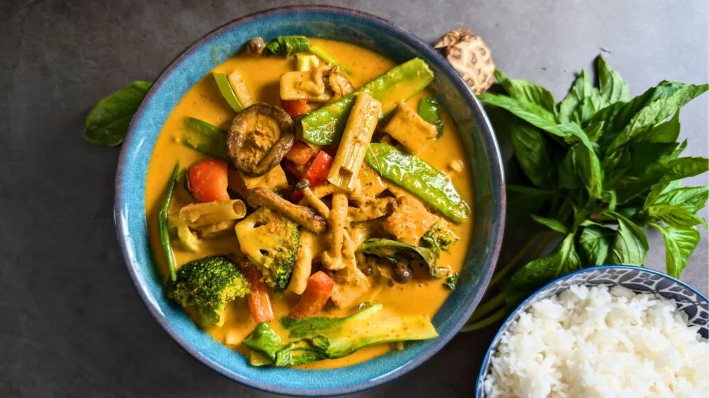 Vegan Panang Curry is served in a Blue bowl with side of Rice