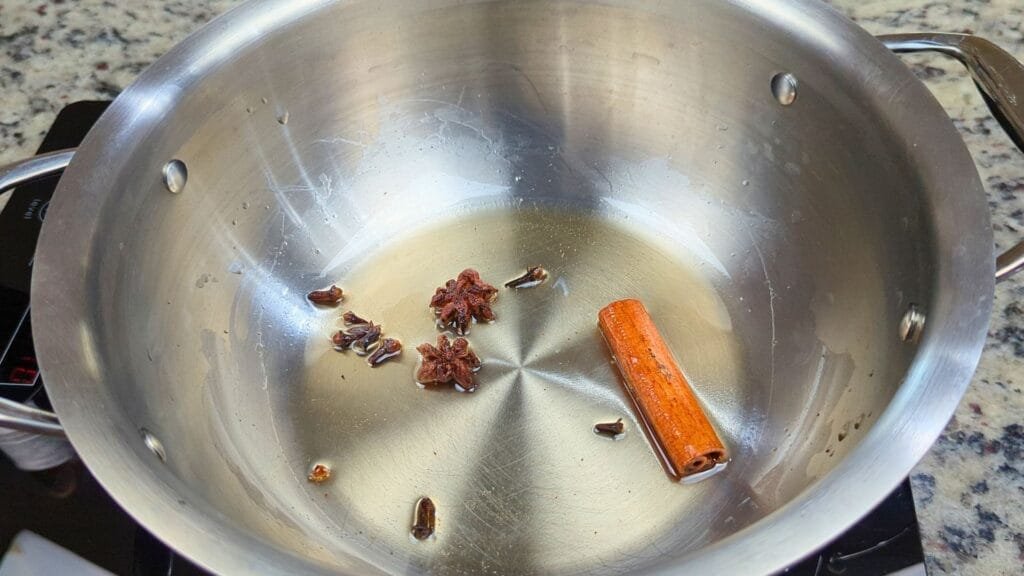 adding Cinnamon stick, star anise and agave nectar in a wok