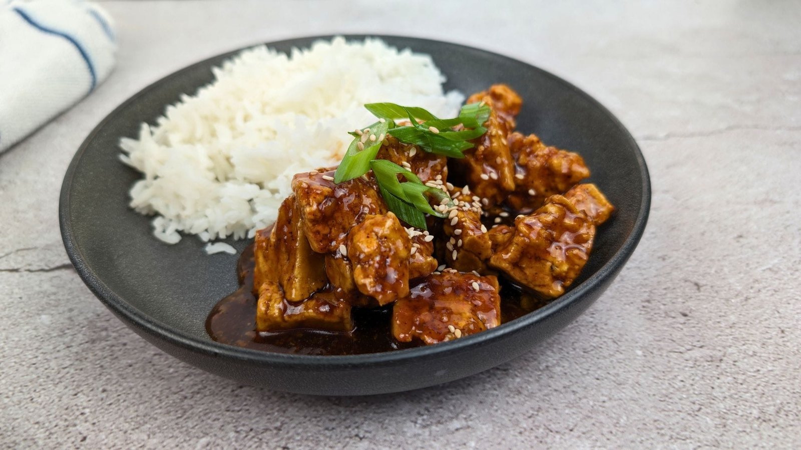 Teriyaki Tofu served in a black bowl