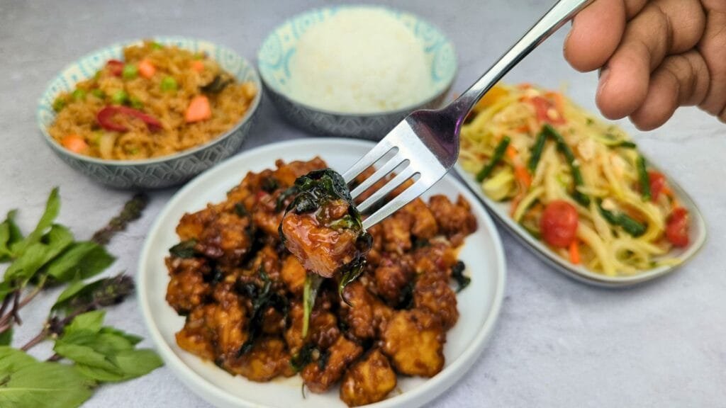 Thai Basil Tofu Stir-Fry (Pad Krapow) is served with the side of Fried Rice and Papaya Salad