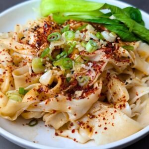 Biang Biang Noodles with bok choy in a white bowl