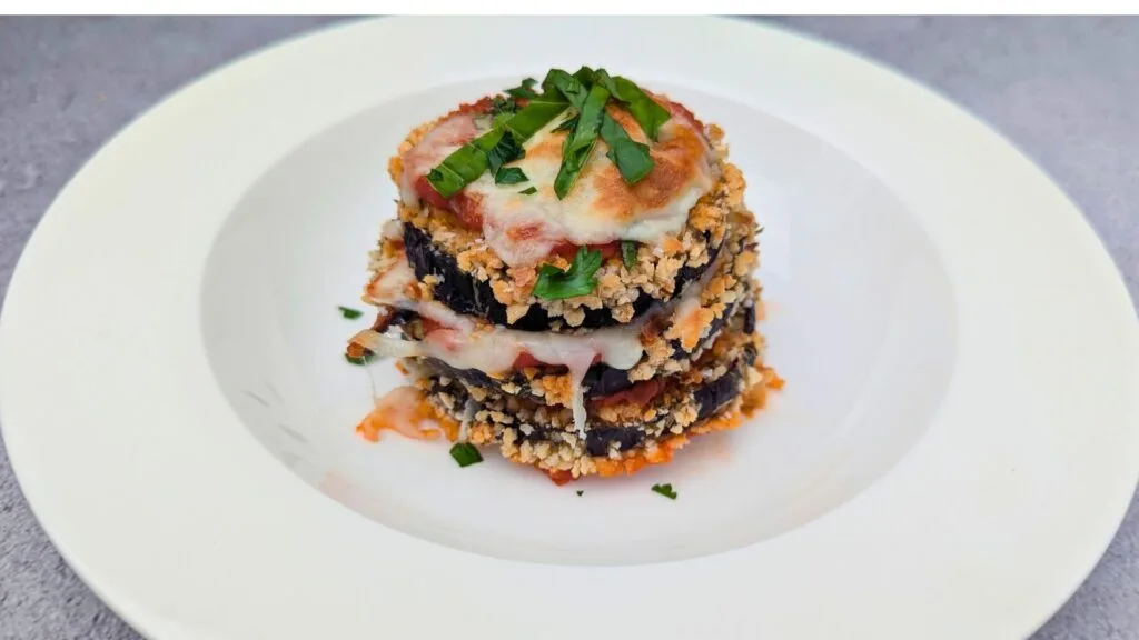 Crispy Eggplant Parmesan is ready and served in a White plate